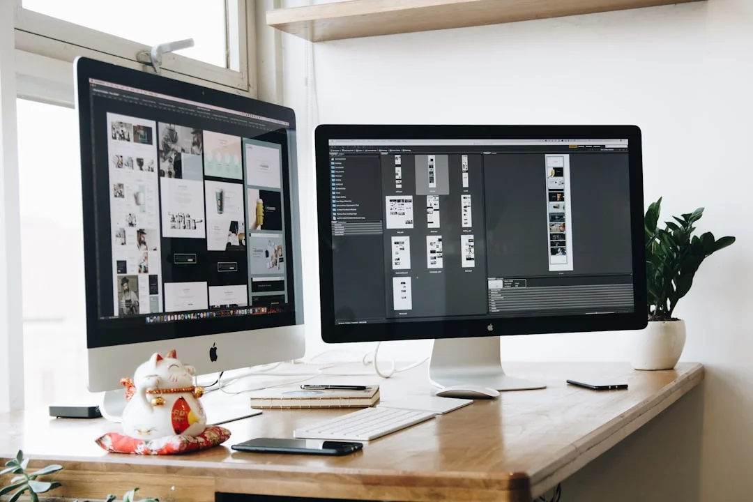 Un espace de travail moderne avec deux écrans d’ordinateur affichant des projets de conception web, mettant en avant la technologie et la productivité.